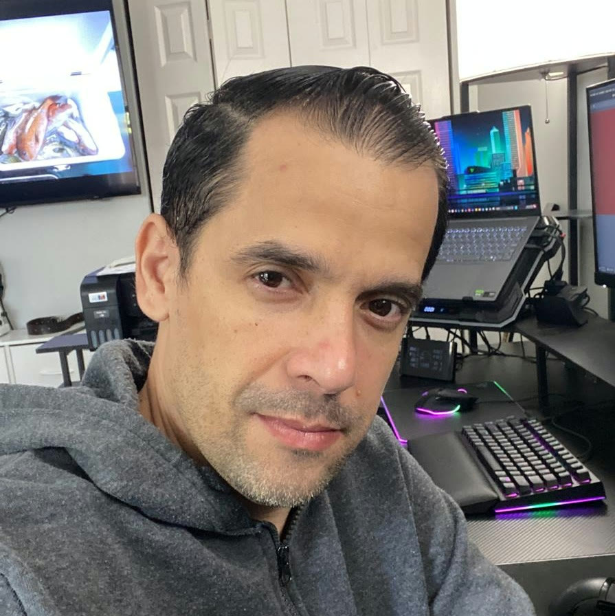 Ivan Carmenates at his desk, with a laptop and an RGB keyboard behind him